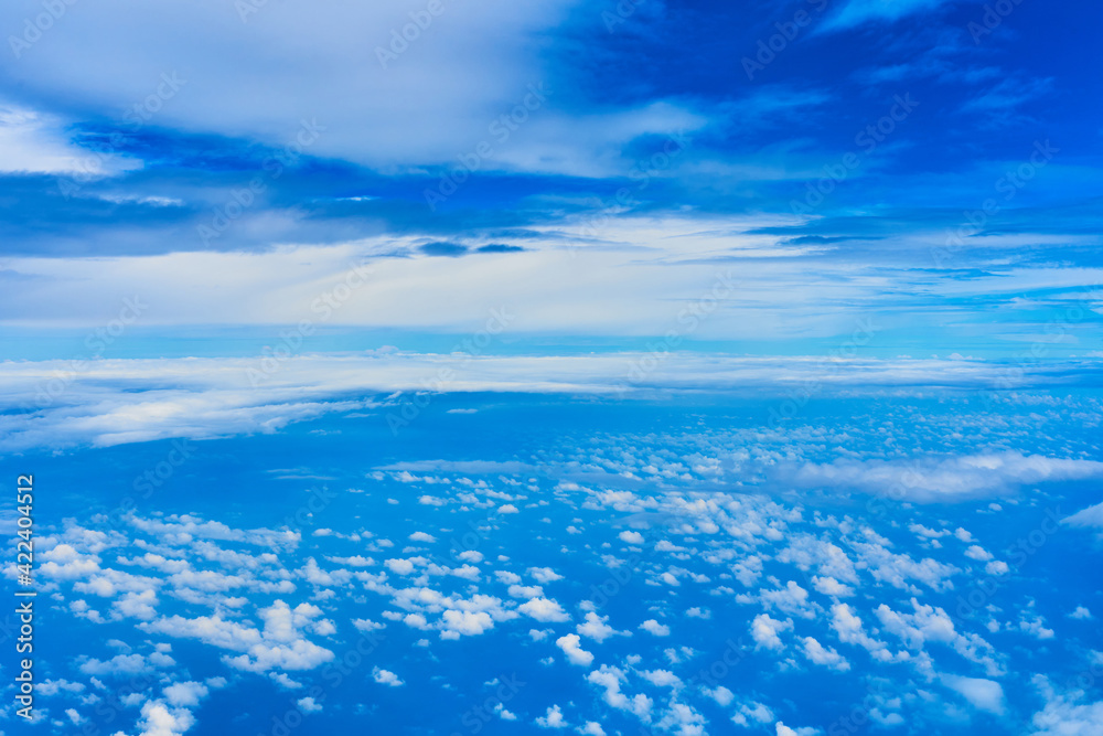 Landscape of fluffy white clouds on a dark blue sky. View from the plane at high altitude