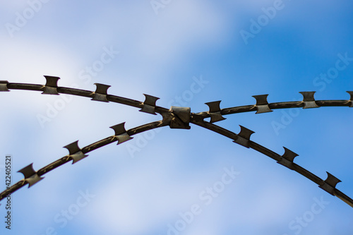 x shape razor wire fence against blue sky
