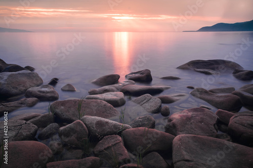  sunset landscape with stones conveys a romantic feeling on a desert coastline with water