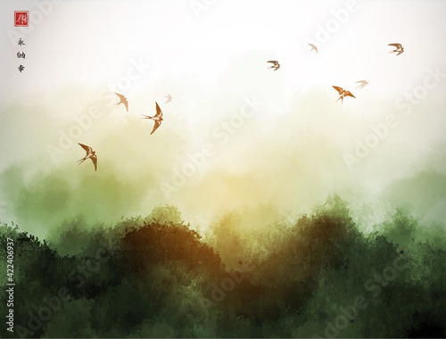 Landscape with green misty forest mountains and flock of swallow birds in the sky. Traditional oriental ink painting sumi-e, u-sin, go-hua. Hieroglyphs - eternity, freedom, happiness, joy
