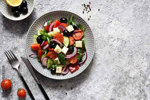 Classic Greek salad with feta and olives on a concrete background.
