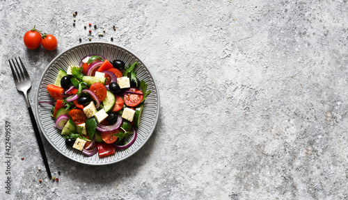 Classic Greek salad with feta and olives on a concrete background.