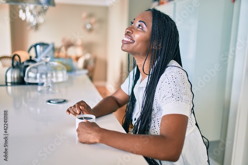 Young african american woman smiling happy drinking cup of coffee at home