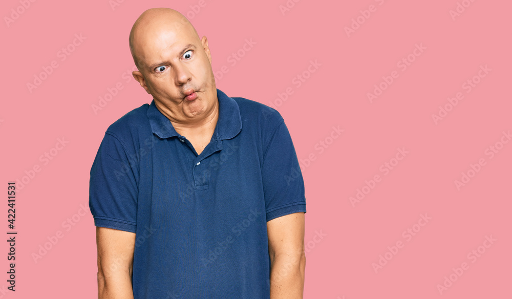Middle age bald man wearing casual clothes making fish face with lips, crazy and comical gesture. funny expression. Middle age bald man wearing casual clothes making fish face with lips, crazy and comical gesture. funny expression.