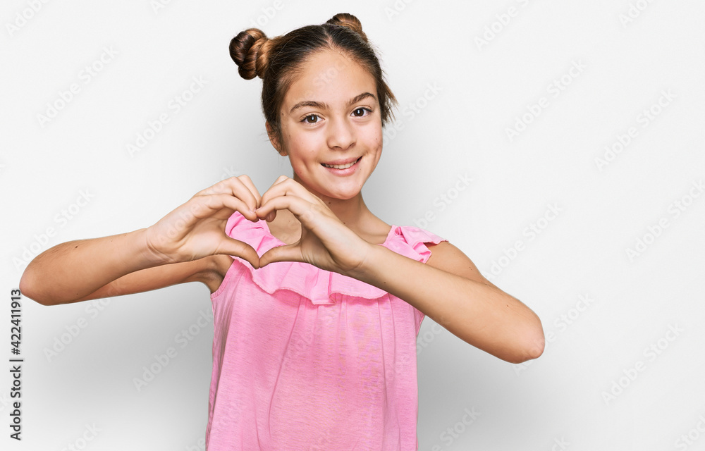 Beautiful brunette little girl wearing summer pink shirt smiling in love showing heart symbol and shape with hands. romantic concept. Beautiful brunette little girl wearing summer pink shirt smiling in love showing heart symbol and shape with hands. romantic concept.