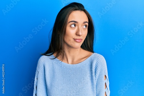 Young hispanic girl wearing casual clothes smiling looking to the side and staring away thinking.