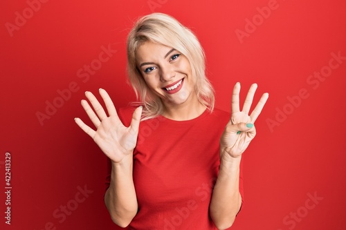 Young blonde girl wearing casual clothes showing and pointing up with fingers number eight while smiling confident and happy.