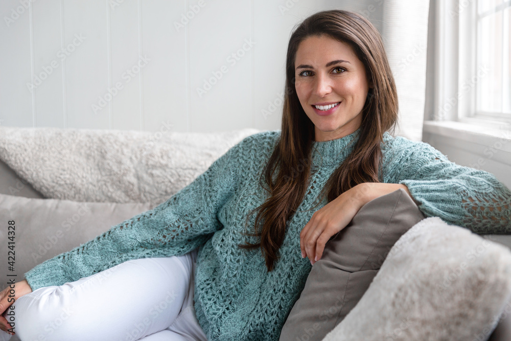 Candid lifestyle head shot of beautiful young woman smiling at home, sitting comfortably and casual on a sofa Candid lifestyle head shot of beautiful young woman smiling at home, sitting comfortably and casual on a sofa