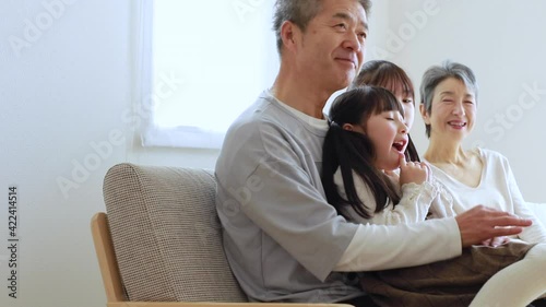 ソファに座りくつろぐ日本人シニア夫婦と孫