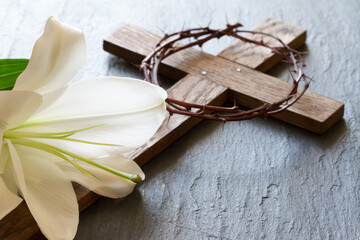 Cross and white lily on black marble background. Passion and resurrection of Christ concept 