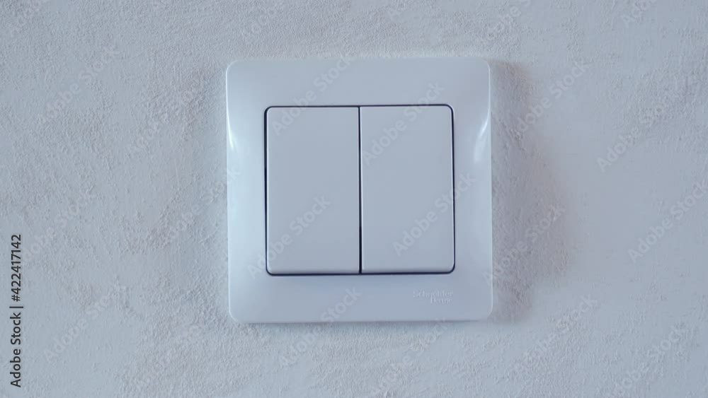Hand turning the light switch on and off.