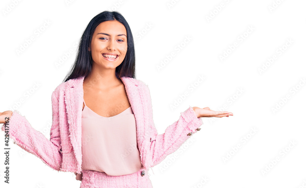 Young beautiful latin girl wearing business clothes smiling showing both hands open palms, presenting and advertising comparison and balance Young beautiful latin girl wearing business clothes smiling showing both hands open palms, presenting and advertising comparison and balance