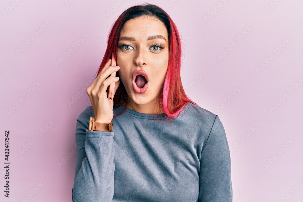 Young caucasian woman having conversation talking on the smartphone scared and amazed with open mouth for surprise, disbelief face Young caucasian woman having conversation talking on the smartphone scared and amazed with open mouth for surprise, disbelief face