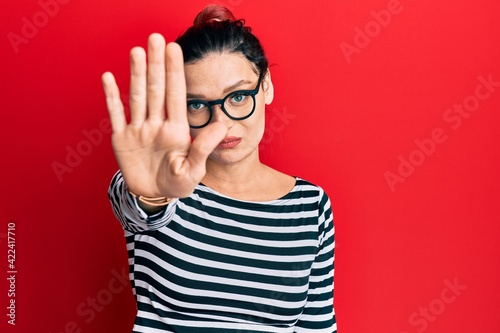 Young caucasian woman wearing casual clothes and glasses doing stop sing with palm of the hand. warning expression with negative and serious gesture on the face.