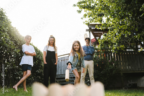 Girl playing molkky with family in back yard photo