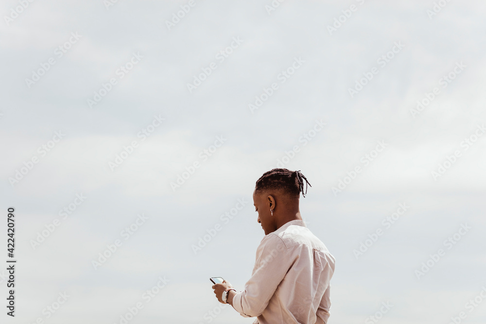 Young man using smart phone against clear sky on sunny day Young man using smart phone against clear sky on sunny day