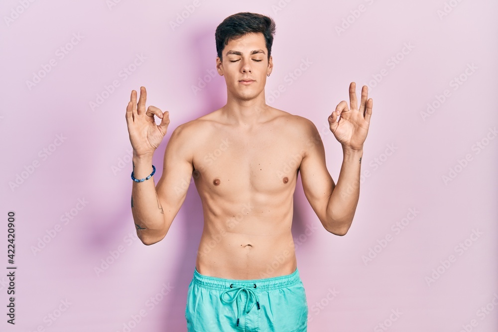 Young hispanic man wearing swimwear shirtless relax and smiling with eyes closed doing meditation gesture with fingers. yoga concept.