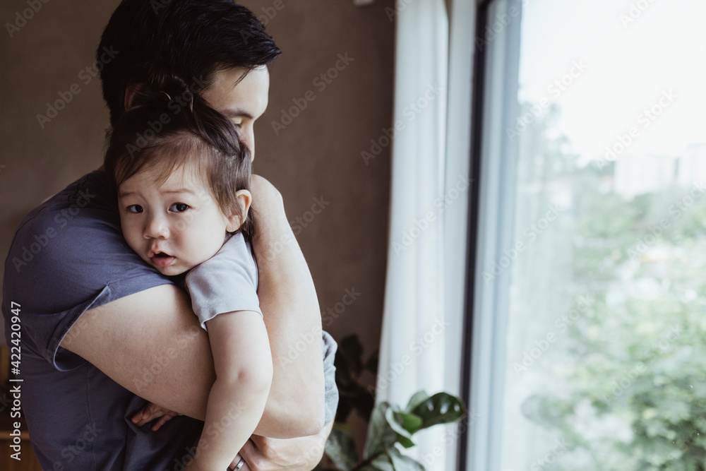 Father carrying baby son by window at home Father carrying baby son by window at home