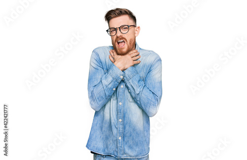 Young redhead man wearing casual denim shirt shouting and suffocate because painful strangle. health problem. asphyxiate and suicide concept.