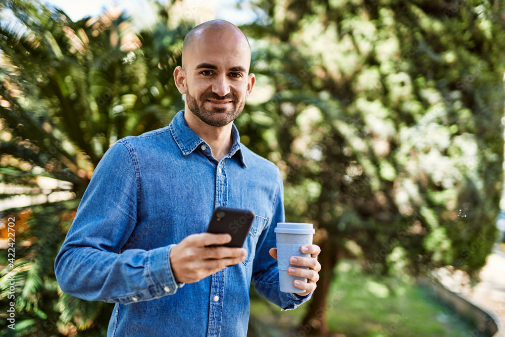 Young hispanic man using smartphone and drinking coffee at the park. Young hispanic man using smartphone and drinking coffee at the park.