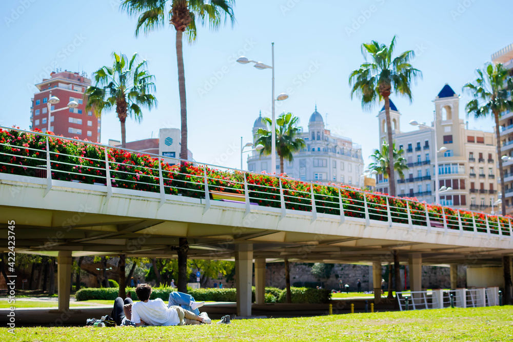 Jóvenes tomando el sol junto a viejo cauce del río Túria (Valencia-España), en un día primaveral.