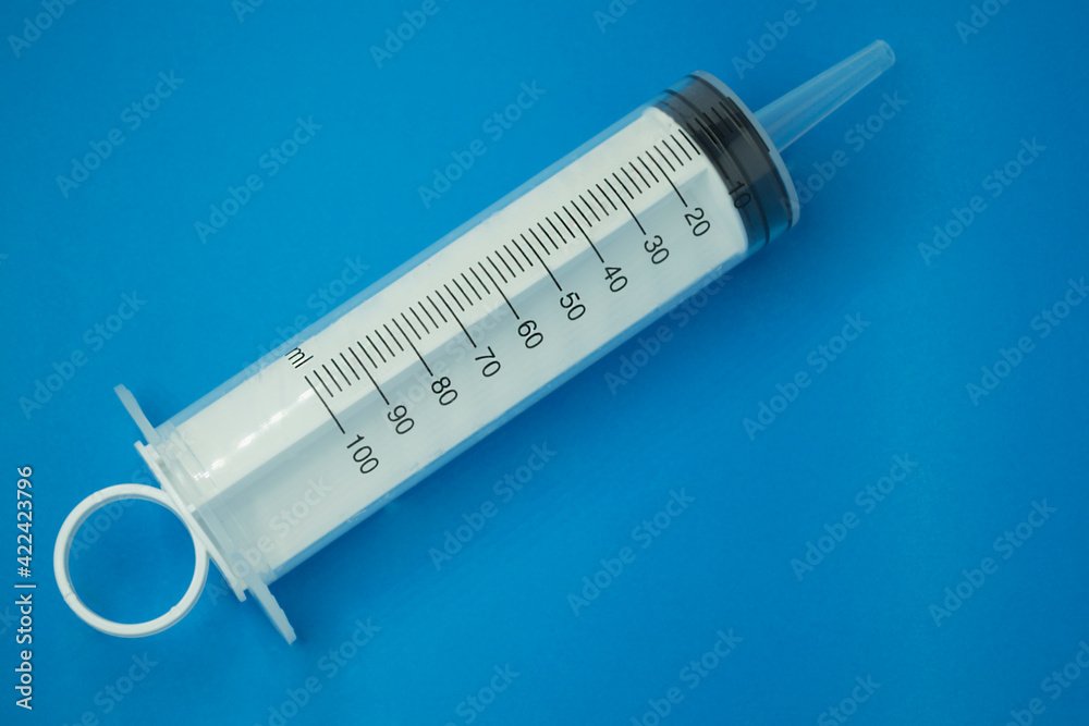 plastic large syringe 100 ml, on a blue background. plastic large syringe 100 ml, on a blue background.