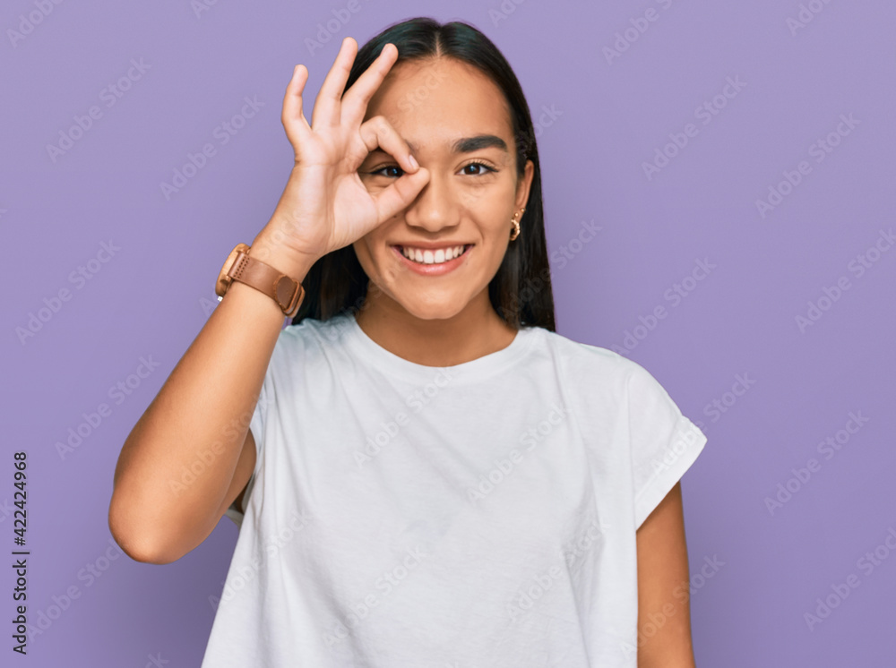 Young asian woman wearing casual white t shirt doing ok gesture with hand smiling, eye looking through fingers with happy face. Young asian woman wearing casual white t shirt doing ok gesture with hand smiling, eye looking through fingers with happy face.