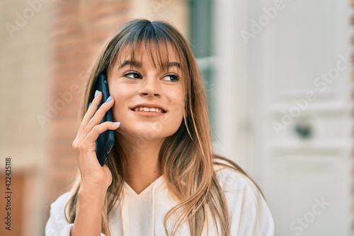 Caucasian sporty teenager girl smiling happy talking on the smartphone at the city.