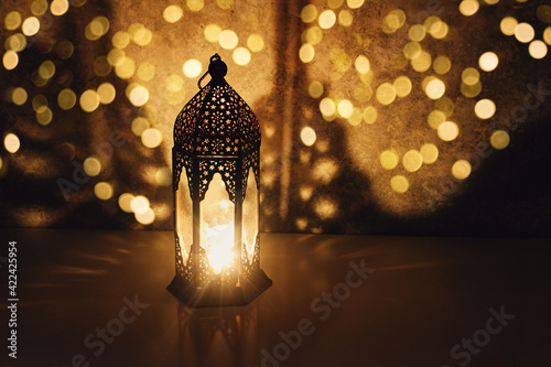 Dark ornamental Moroccan lantern burning at night. Muslim holiday Ramadan Kareem festive blurred background. Glittering bokeh lights and decorative shadows. Islam, iftar dinner concept. photo