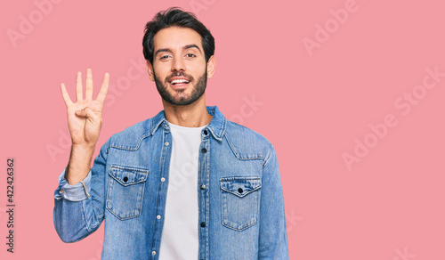 Young hispanic man wearing casual clothes showing and pointing up with fingers number four while smiling confident and happy.