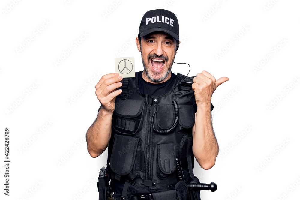 Middle age policeman wearing police uniform holding reminder paper with peace symbol pointing thumb up to the side smiling happy with open mouth Middle age policeman wearing police uniform holding reminder paper with peace symbol pointing thumb up to the side smiling happy with open mouth