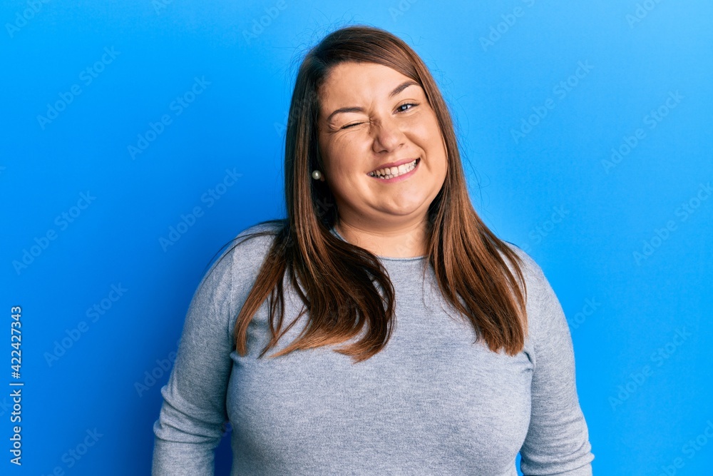 Beautiful brunette plus size woman wearing casual clothes winking looking at the camera with sexy expression, cheerful and happy face. Beautiful brunette plus size woman wearing casual clothes winking looking at the camera with sexy expression, cheerful and happy face.