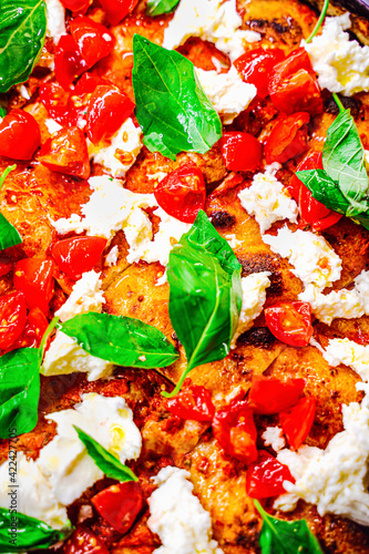 Close up of a mouth watering gourmet pizza with buffalo mozzarella cheese, cherry tomatoes and basil leaves photo