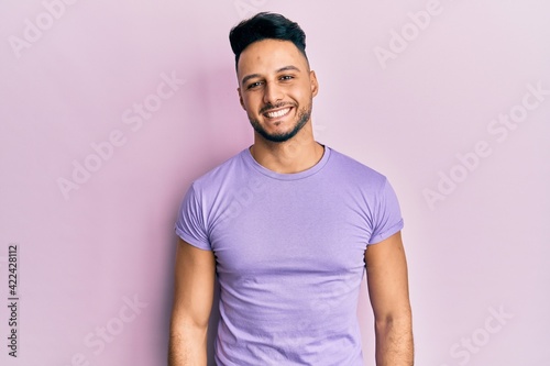 Young arab man wearing casual clothes looking positive and happy standing and smiling with a confident smile showing teeth