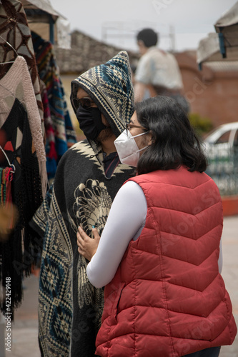 a couple in love together at a local handicrafts, they wear a traditional poncho and the other person a vest with jean and a mask, travel in the day