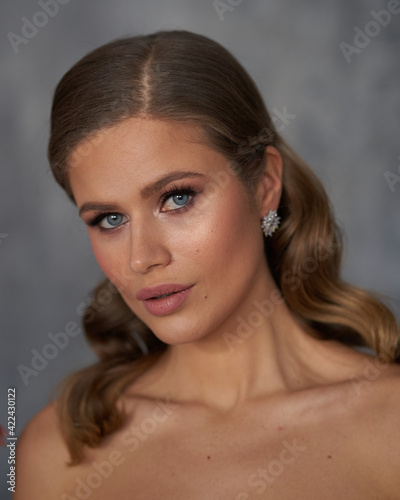 Young beautiful tanned caucasian woman face portrait. Elegant lady with wavy hair hairstyle