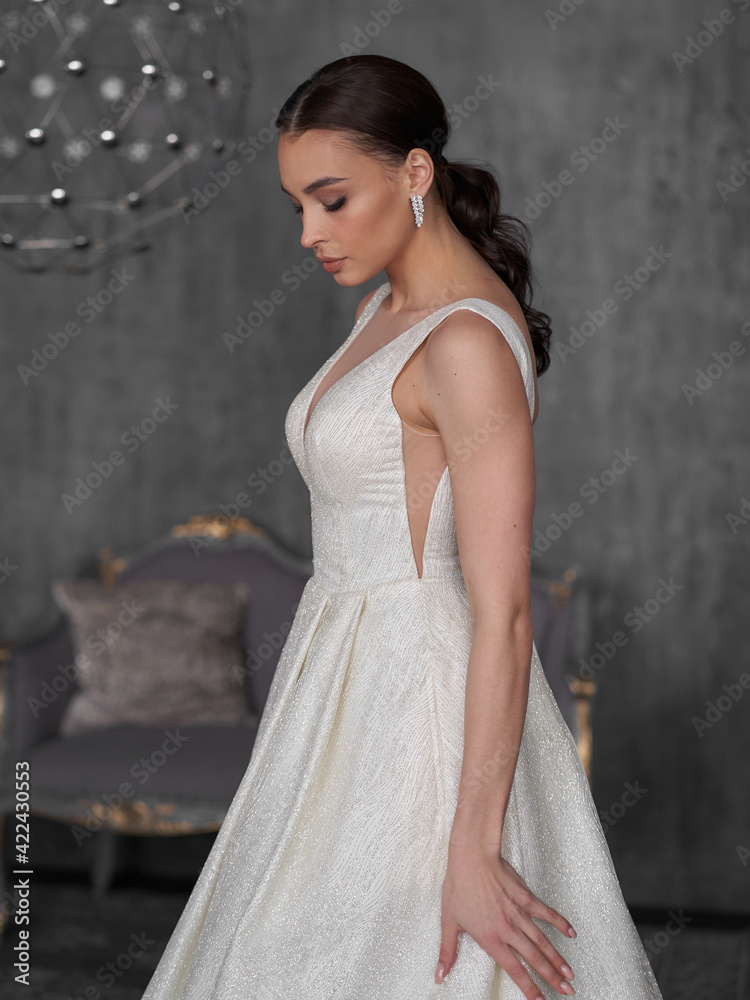 Bride portrait. Elegant woman wearing white wedding dress. Female model with perfect natural make-up and pony tail hairstyle. Brunette woman Bride portrait. Elegant woman wearing white wedding dress. Female model with perfect natural make-up and pony tail hairstyle. Brunette woman