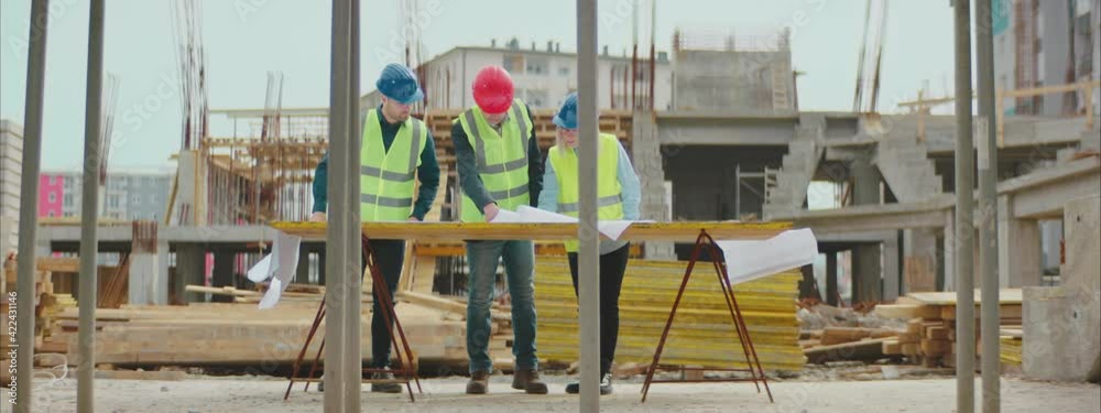 A team of Architects examining the engineering blueprints on the commercial Construction Site. A team of Architects examining the engineering blueprints on the commercial Construction Site.