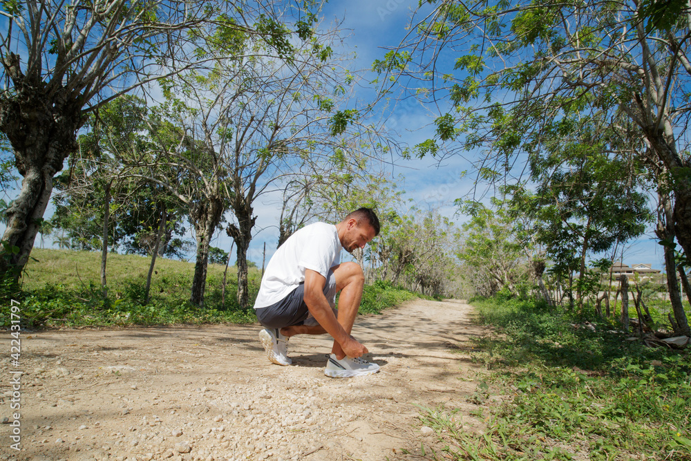 Runner sportsman tying shoelaces in nature.