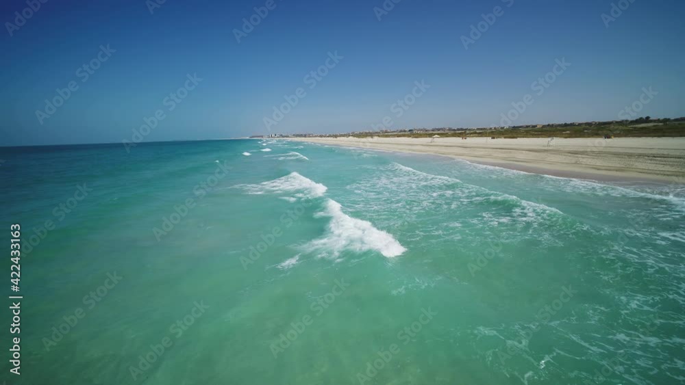 Aerial view of turquoise waves rolling on the golden beach near Dubai, United Arab Emirates