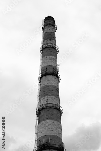 A huge red brick pipe for a gas boiler house built in the USSR was photographed against a cloudy sky.