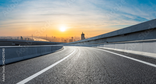 Asphalt road and city skyline at sunrise in Shanghai.