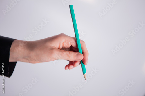 Hand holding a green pencil on white background