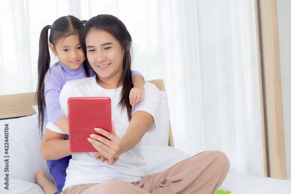 Young asian mom and daughter video call on tablet computer greeting with family together, happy mother and girl with relationship using technology in communication to internet online, two people. Young asian mom and daughter video call on tablet computer greeting with family together, happy mother and girl with relationship using technology in communication to internet online, two people.