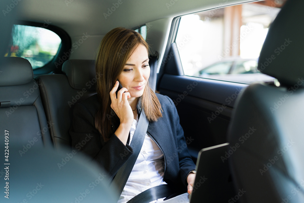 Professional pretty woman mutlitasking during a car ride