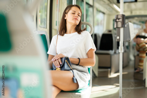 Tired girl sleeps sitting on seat in tram