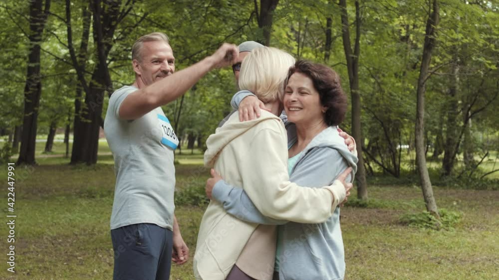 Medium shot of several aged Caucasian sporty men and women wearing sportswear meeting in park before a race Medium shot of several aged Caucasian sporty men and women wearing sportswear meeting in park before a race