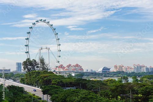 Big ferris wheel in the modern city skyline in Singapore.