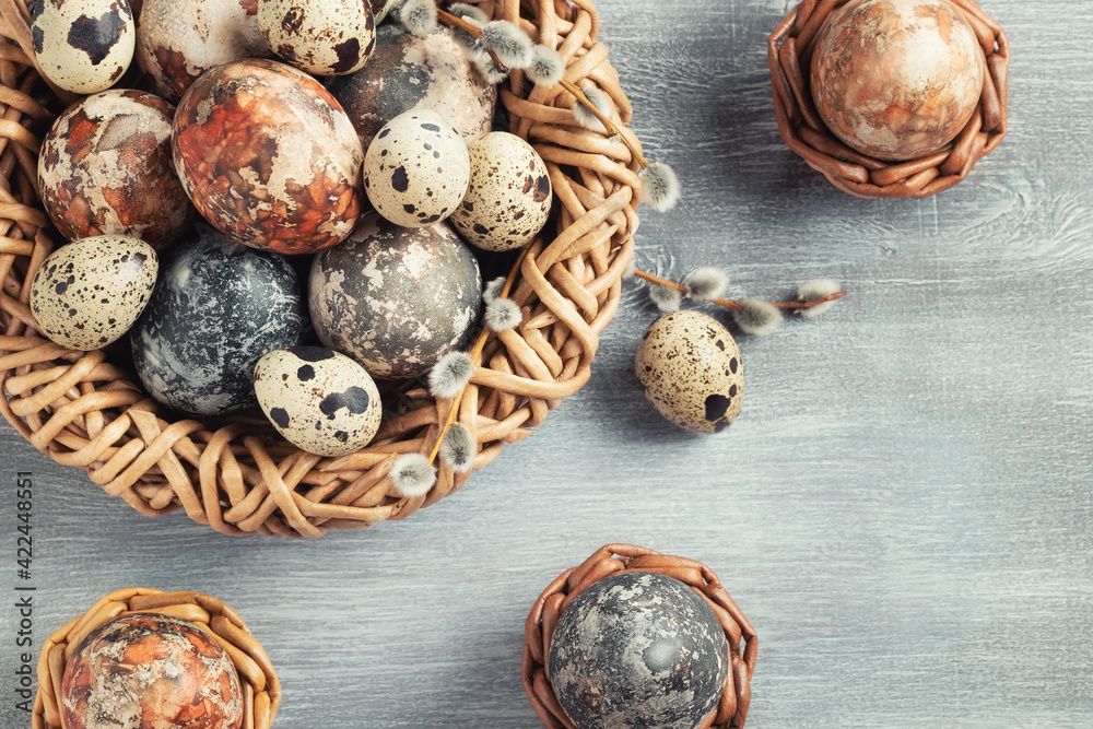Easter composition - several marble eggs painted with natural dyes in a wicker nest and baskets, top veiw Easter composition - several marble eggs painted with natural dyes in a wicker nest and baskets, top veiw