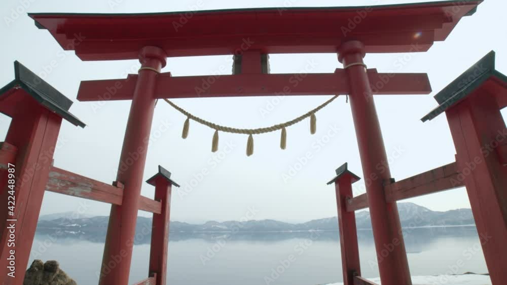Traditional japanese gate near a mirror-like reflective crater-lake. A sacred torii gate near the deepest lake in japan, tazawa-lake in akita prefecture Traditional japanese gate near a mirror-like reflective crater-lake. A sacred torii gate near the deepest lake in japan, tazawa-lake in akita prefecture